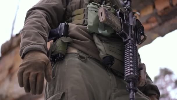 Nerozpoznatelný ozbrojený běloch stojící venku v rozbořeném městě a mířící pistolí. Odvážný voják v rusko-ukrajinské válce ve zničeném městě. Armádní a obranný koncept. — Stock video