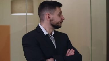 Yakışıklı, esmer, sakallı, kahverengi gözlü, elleri çaprazlanmış beyaz adamın yakın plan portresi. Sabırsız ciddi iş adamı iç çekip gidiyor. Özgüven ve yaşam tarzı.