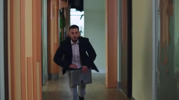 Широко снятый офисный коридор с торопливым человеком, бегущим мимо отъезда. Непунктуальный кавказский менеджер опаздывает на деловую встречу в закрытом помещении. Концепция стиля жизни и пунктуальности. — стоковое видео
