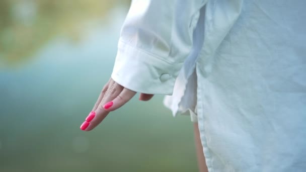 Close-up mulher irreconhecível e menina de mãos dadas no fundo do lago rio ao ar livre. Mãe e filha caucasiana desfrutando de lazer no parque de verão da primavera. Conceito de amor familiar. — Vídeo de Stock