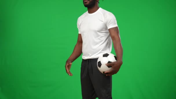 Tatuerad oigenkännlig afroamerikansk idrottsman med fotboll står vid chromakey bakgrund. Självsäker seriös fotbollsspelare på grön skärm väntar mästerskap match. — Stockvideo