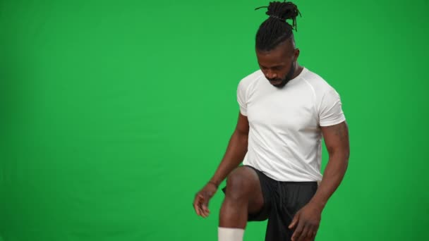 Πορτρέτο της αυτοπεποίθηση της Αφρικής Αμερικανός αθλητής πασάροντας μπάλα κάτω διασχίζοντας τα χέρια κοιτάζοντας κάμερα. Όμορφος ποδοσφαιριστής που ποζάρει στο φόντο chromakey σε πράσινο πρότυπο οθόνης. — Αρχείο Βίντεο
