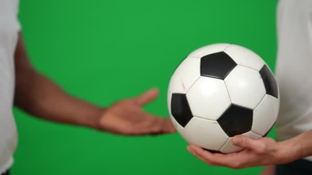 Close-up männliche kaukasische und afroamerikanische Hände beim Fußballspielen auf der grünen Leinwand. Unerkennbare Sportler auf Chromakey-Hintergrund-Vorlage. Fußball- und Wettkampfkonzept. — Stockvideo