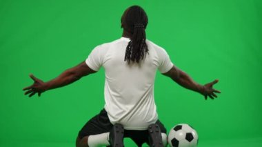 Arka planda zafer kazanan Afro-Amerikan sporcu kromakey arka planda dizlerinin üzerinde oturuyor ve ellerini uzatıyor. Başarılı, memnun futbolcu yeşil ekranda zafer golü atıyor. Şablon modellemesi.