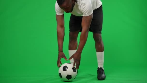 Motivated African American man checking football ball kicking running away leaving green screen. Inspired soccer player playing game. Championship and sport concept. — стоковое видео