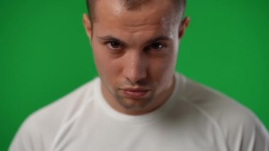 Kameraya gülümseyen futbol topuyla terleyen beyaz sporcunun yakın plan portresi. Kromakey arka planda poz veren yakışıklı genç adamın ön görüntüsü..