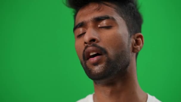 Close-up exhausted Middle Eastern perspiring sportsman looking at camera smiling wiping sweat off face. Portrait of tired satisfied football player posing at green screen chromakey background. — Stock Video