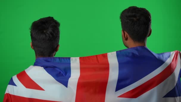 Back view positive mellemøstlige venner gestikulerer succes støtte britiske fodboldhold på grøn skærm. Glade tilfredse sportsfans pakket ind i nationalt flag glædeligt mål taler smilende. – Stock-video