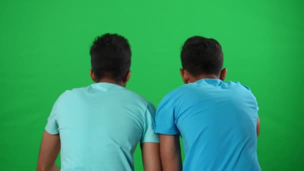 Zwei inspirierte junge Männer aus dem Nahen Osten, die gestikulierend Fußballspiele auf grünem Bildschirm verfolgen. Motivierte Fußballfans jubeln unterstützendem Team bei chromakey Hintergrundvorlage zu. — Stockvideo