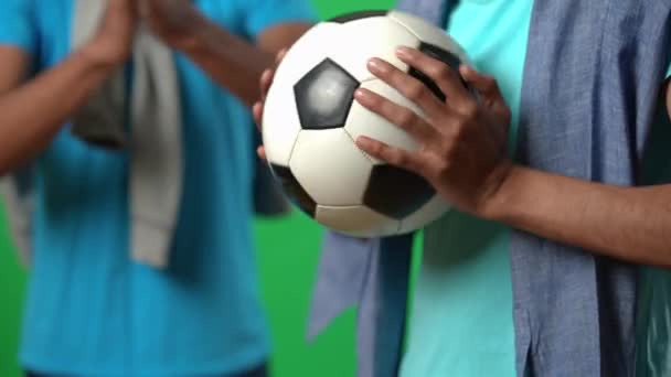 Ball in hands of excited Middle Eastern football fan cheering with friend on green screen. Unrecognizable young men supporting national team on championship at chromakey background. — Stock Video