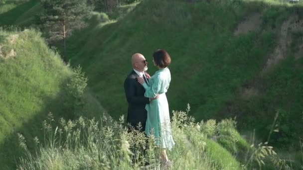High angle view loving Caucasian man and woman talking in slow motion standing in sunshine at background of green landscape. Wide shot happy couple dating outdoors on sunny spring day. — ストック動画