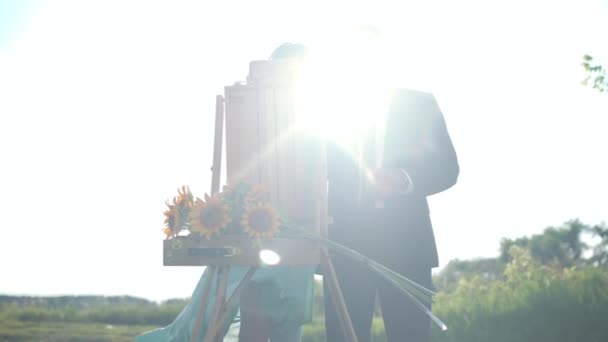 Портрет елегантного чоловіка в костюмі, де жінка стоїть у сонячному промінні на вулиці. Передній вид зосереджений на талановитих кавказьких дорослих подружжях, які насолоджуються дозвіллям на відкритому повітрі на сонячному весняному лузі влітку.. — стокове відео