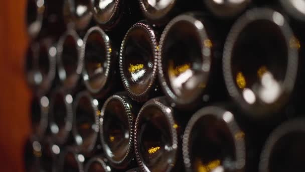 Wine bottle bottoms stacked in wine cellar indoors. Dark glass containers with high-quality alcohol beverage indoors in winery. Wine production concept. — Vídeo de stock