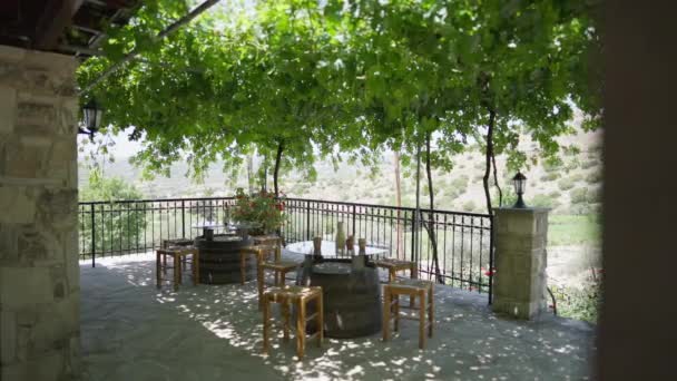 Amplia toma acogedoras mesas auténticas en la terraza en bodega con hermoso paisaje mediterráneo de Chipre en el fondo. Cómodo café al aire libre para la degustación de vinos. Concepto de naturaleza y comodidad. — Vídeos de Stock