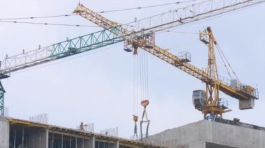 İnşaatçılar yavaş çekimde konuşarak kule vinçleriyle tamamlanmamış gökdelende duruyorlar. Ukrayna 'nın başkenti Kyiv' de gayrimenkul inşa eden profesyonel beyaz adamlar..