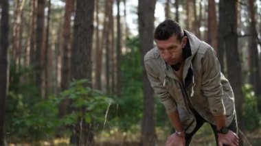 Ormanda durup dinlenmekten yorgun düşmüş bir erkek yürüyüşçü. Ormanlık alanda güneşli bir bahar gününde beyaz bir adamın portresi. Turizm ve aktif yaşam tarzı kavramı.