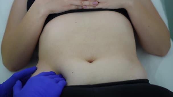 Top view belly of slim young Caucasian woman lying on examination couch with doctor hand pressing abdomen. Unrecognizable man checking ill patient in hospital indoors. Gastrointestinal tract diseases. — Video