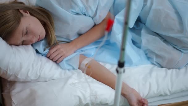 Hög vinkel visa porträtt av deprimerad tonåring flicka med ögondroppar liggande i sängen på sjukhus avdelning. Tankeväckande sorglig vacker kaukasisk tonåring genomgår behandling efter olycka i medicinsk klinik. — Stockvideo