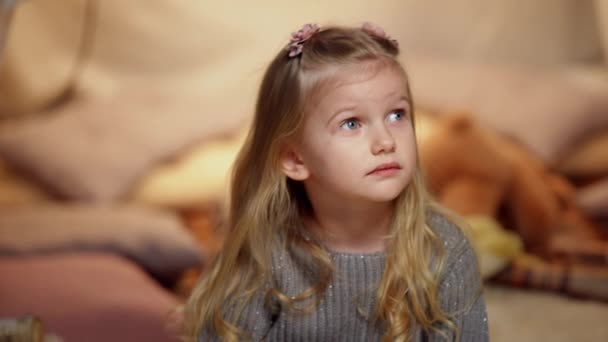 Cute little girl looking up sitting in tent at home with toys. Portrait of pretty charming Caucasian child resting indoors. Slow motion. – Stock-video