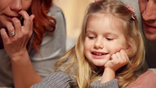 Close-up portrait of charming beautiful little daughter talking in slow motion lying with parents in comfortable tent at home. Headshot of Caucasian child enjoying leisure with mother and father. — Stok video