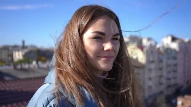 Close-up portrait of beautiful confident young Caucasian woman smiling looking away in sunshine. Happy relaxed millennial lady enjoying sunny morning standing on rooftop in Kyiv Ukraine. — Video