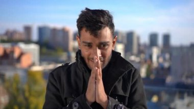 Ön manzara, elleri birarada gülümseyen Orta Doğulu adamın gün ışığında kameraya bakmasını umuyor. Şehir merkezinde çatıda poz veren yakışıklı bir gencin portresi. Umut ve başarı kavramı.