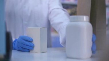 Tanımlanamayan eczacı eczanedeki kasadaki müşteriye kutu ve ilaç veriyor. Kafkasyalı bir satıcı ve kapalı bir eczanede alıcı. İlaç ve sağlık hizmetleri kavramı.