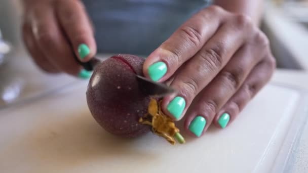 Close-up passievrucht met vrouwelijke hand snijdend fruit op helften. Onherkenbare jonge blanke vrouw bereidt heerlijke lekkere lunch binnen in de keuken. — Stockvideo
