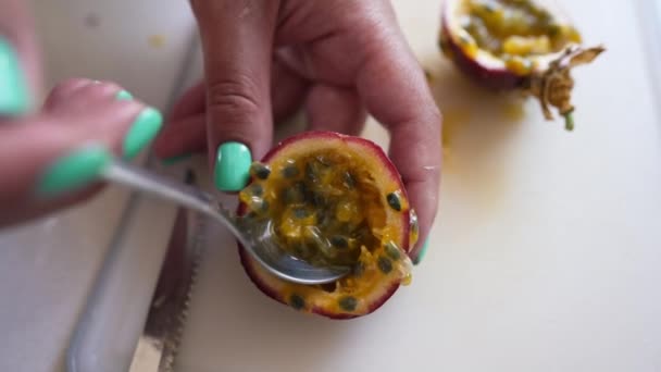Top view passion fruit on white table with female hand taking inside with spoon. Unrecognizable young Caucasian woman eating tasty sweet healthful dessert indoors. — Wideo stockowe
