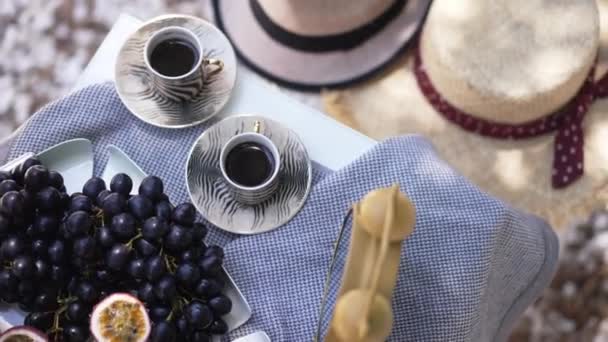 Top view table with delicious black coffee and tasty healthful vitamin fruits on sunny day outdoors. Freshly brewed espresso, grapes, apples, peaches, passion fruit, orange and lime on terrace. — Stock Video