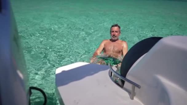 Satisfait homme caucasien nageant loin du yacht dans la mer Méditerranée turquoise au ralenti. Touriste masculin adulte profitant d'une journée d'été ensoleillée sur Chypre dans la lagune. — Video