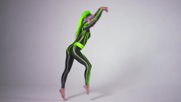 Mladý fit gymnastka dělá vzdušný chodec a zpět handspring ve zpomaleném filmu. Široký záběr flexibilní běloška štíhlá žena v futuristickém kostýmu vystoupení na bílém pozadí. — Stock video