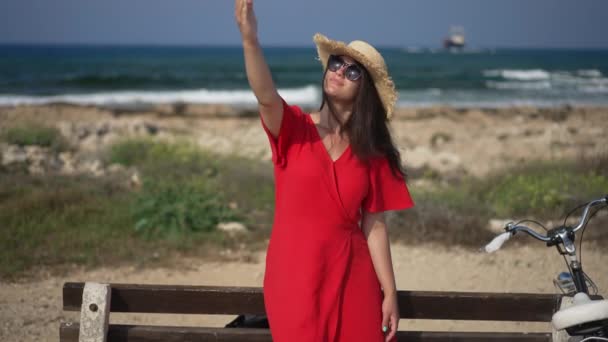 Young beautiful woman looking up at sunshine standing on Mediterranean sea beach on Cyprus. Portrait of happy smiling positive Caucasian tourist enjoying sunny day outdoors. Slow motion. — Stock Video