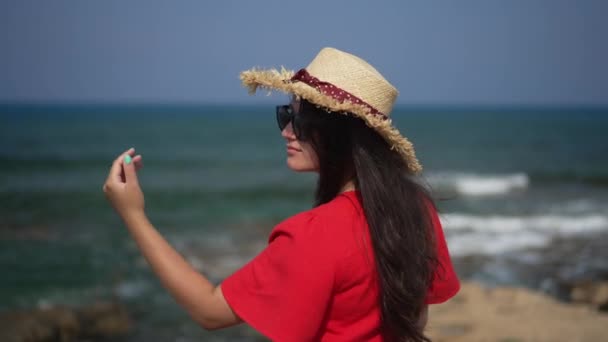Shooting over shoulder of young Caucasian woman looking at camera smiling standing on beach at Mediterranean sea. Happy millennial tourist posing in slow motion on summer vacations. — Video Stock