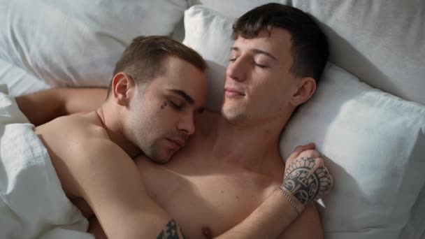 Лучшая кавказская гей-пара спит в постели по утрам дома. Расслабленные красивые мужчины обнимаются в спальне с закрытыми глазами. Концепция образа жизни и однополых отношений. — стоковое видео