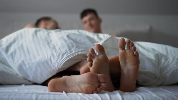 Nahaufnahme eines bis zur Unkenntlichkeit verschwommenen schwulen Paares, das morgens im Bett kuschelt. Fröhlich unbeschwert entspannte kaukasische junge Männer genießen Freizeit im Schlafzimmer drinnen. — Stockvideo