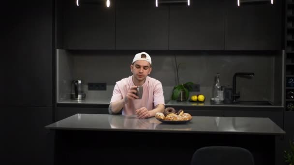 Портрет уверенного счастливого гея, пьющего кофе на кухне, как партнера, входящего в обнимающего парня. Позитивная кавказская молодая ЛГБТК-пара, наслаждающаяся утром дома. — стоковое видео