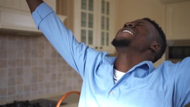 Eccitato soddisfatto giovane uomo allungando le mani in piedi in cucina a casa all'interno. Ritratto di ragazzo felice afroamericano che distoglie lo sguardo sorridente. — Video Stock