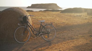 Kıbrıs 'ta altın gün batımında geniş ölçekli sarı buğday tarlası. Arka planda Akdeniz manzarası ve bisikleti olan güzel bir manzara. Yavaş çekim.