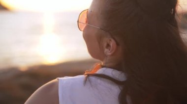 Gün ışığında yavaşça dans eden neşeli, genç bir kadının omzunun üstünden çekim yapmak. Arka manzara mutlu Kafkasyalı turist sağdaki Akdeniz sahilinde eğleniyor..