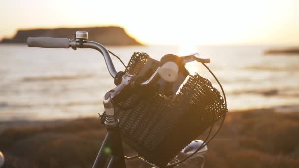 Cesta de cierre en el volante de la bicicleta en los rayos del sol en el crepúsculo. Bicicleta en rayo de sol dorado al atardecer en Chipre al aire libre. Belleza de la naturaleza y concepto deportivo. — Vídeo de stock
