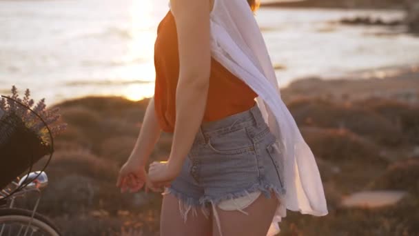 Nerozpoznatelná štíhlá žena tančící zpomaleně ve slunečním svitu venku na pláži Středozemního moře. Šťastný kavkazský mladý žena turista s kole těší letní volný čas na dovolené. — Stock video