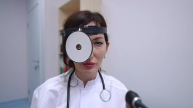 Kafkas kadın otolarolog portresi. Tıbbi ekipmanlarla ağır çekimde poz veriyor. Güzel bir kadın kameraya bakıp gülümsüyor. Hastanedeki iş yerinde kapalı alanda oturuyor.
