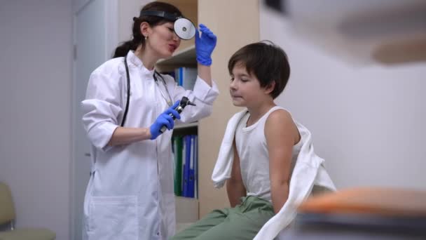 Кавказький Хлопчик Сидить Дивані Усміхнений Лікар Який Перевіряє Вуха Отоскопом — стокове відео