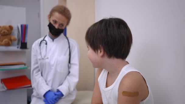 不满的白人男孩肩膀上有医疗补丁 回头看着戴着眼镜片的模糊医生 在疫苗中心接受Covid 19药物治疗的可悲病人 预防疾病 — 图库视频影像