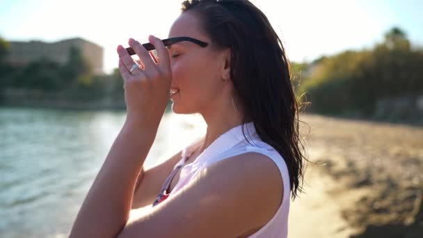 Vista Lateral Sonriente Mujer Joven Que Pone Gafas Sol Mirando — Vídeo de stock