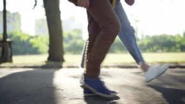 Aynı anda güneş ışığında yürüyen genç bir çiftin yan görüş bacakları. Tanımlanamayan beyaz bir oğlan ve kız yaz parkında güneş ışığında geziniyorlar. Boş zaman ve yaşam tarzı konsepti