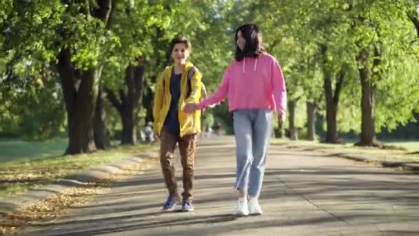 Долли Сняла Счастливую Беззаботную Любящую Подростковую Пару Прогуливающуюся Солнцем Аллее — стоковое видео