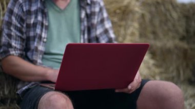 Samanlıkta dizüstü bilgisayarı olan tanınmayan beyaz bir genç adam. Klavye mesajında yazan serbest çalışan bir erkek. Yavaş çekim