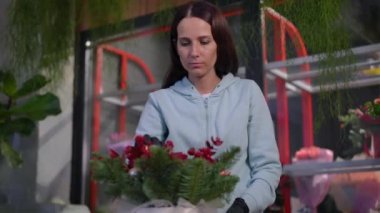 Çiçekçiden çiçeğe dönüşen tatmin olmuş bir portre atölyede gülümsüyor. Beyaz yetenekli, zayıf, güzel bir kadın. Kapalı alandaki çiçekçide buket yapıyor.